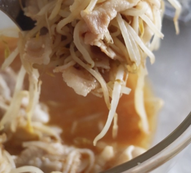 電子レンジで加熱調理された豚バラ肉ともやしの味噌だれがボウルの中でよく混ざり合い、スプーンですくわれている様子。そうめんに合う絶品具材。
