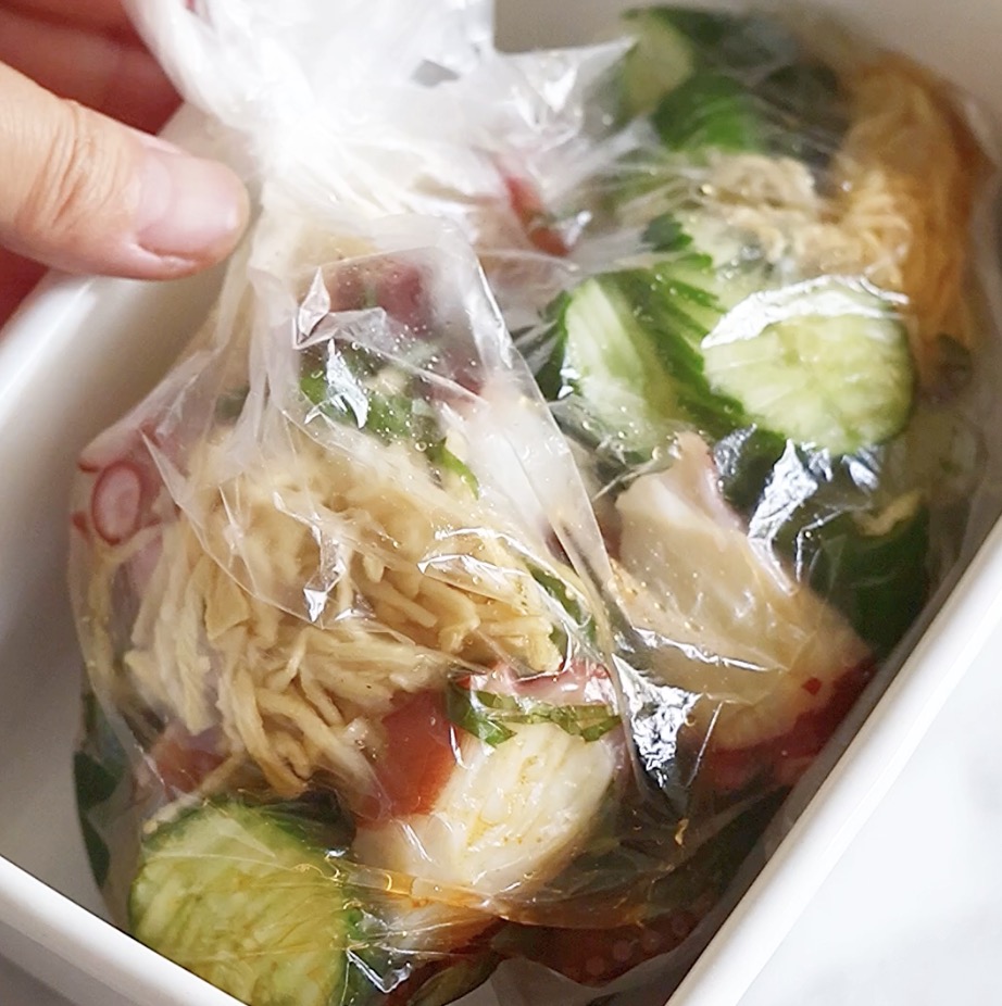 ポリ袋の口を閉じて、酢の物の具材と調味液を揉み込み、全体に味をしっかり馴染ませている様子