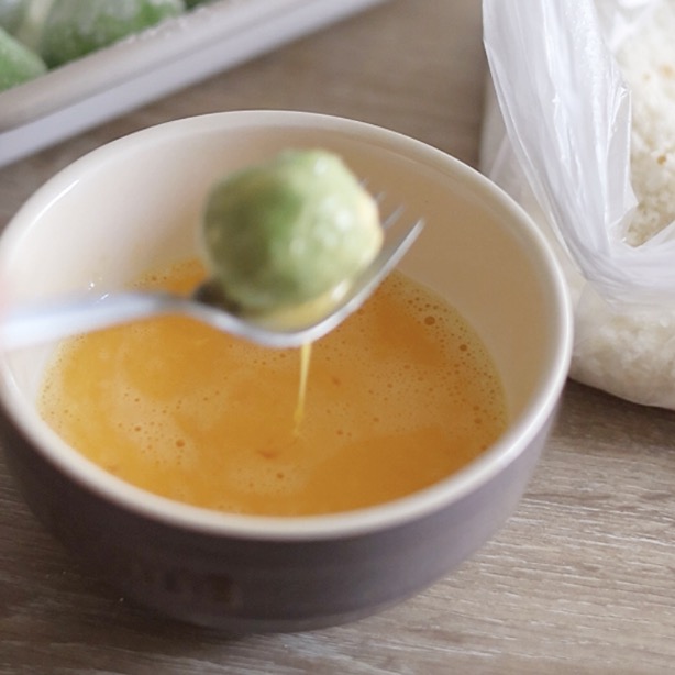 薄力粉をふったえんどう豆コロッケに卵をくぐらせる