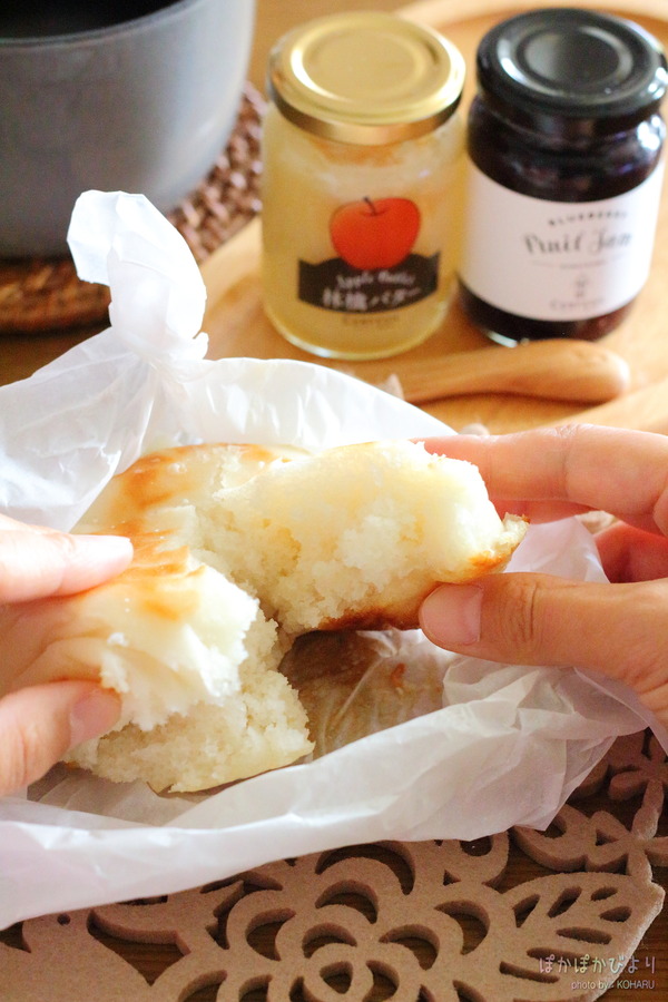 手でちぎられた米粉パンの断面。中のふわふわもちもちした食感がよくわかる。後ろにはジャムの瓶があり、朝食やおやつにぴったりのグルテンフリーパン