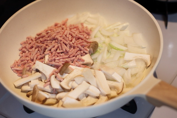 白いフライパンで炒め始める前の、合いびき肉、スライスしたたまねぎ、エリンギ。ちくわボロネーゼ風の具材。