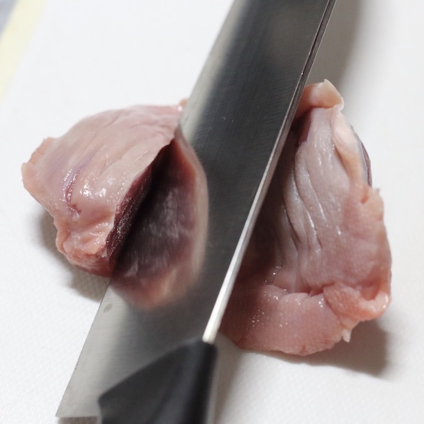 砂肝を包丁で半分に切る様子。
