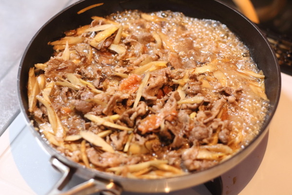 フライパンで炒めた牛肉やごぼうの色が変わってきたら、牛しぐれ煮の調味料を加えて軽く煮込む