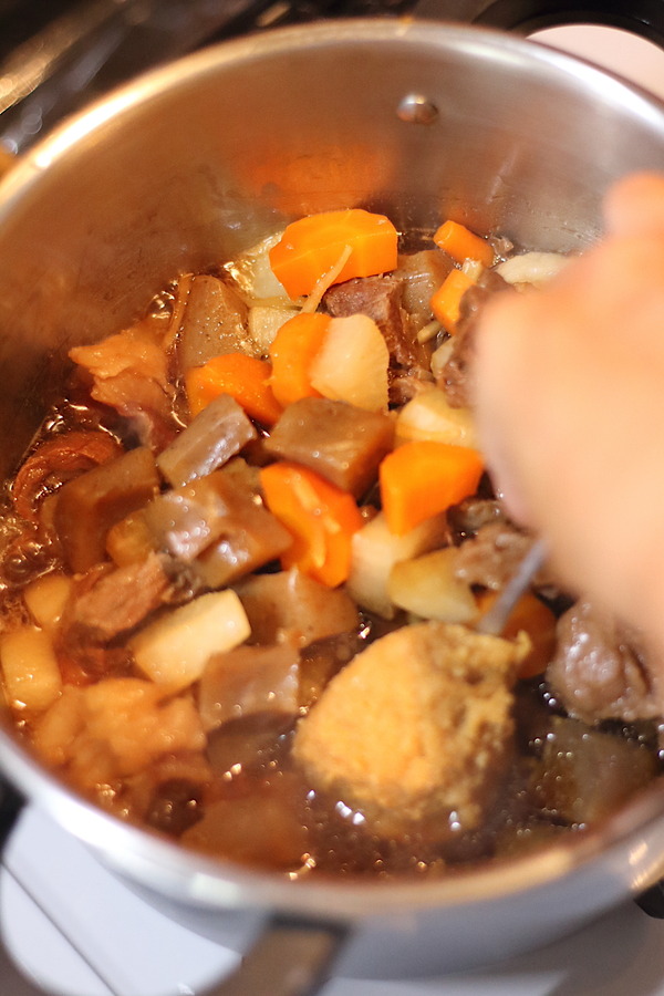 圧力鍋で煮込まれている牛すじこんにゃく煮込み。具材の牛すじ肉、にんじん、大根、こんにゃくがしっかりと煮込まれ、味が染み込んでいる様子。