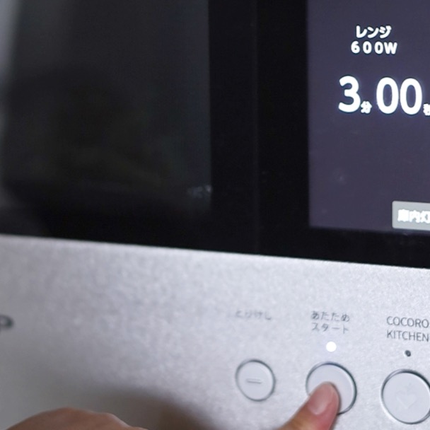 電子レンジで600W3分の設定が表示され、加熱開始ボタンを押している手。時短レンジ調理