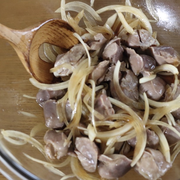 ボウルに入った砂肝と玉ねぎに調味料を加え、木べらで混ぜ合わせる様子