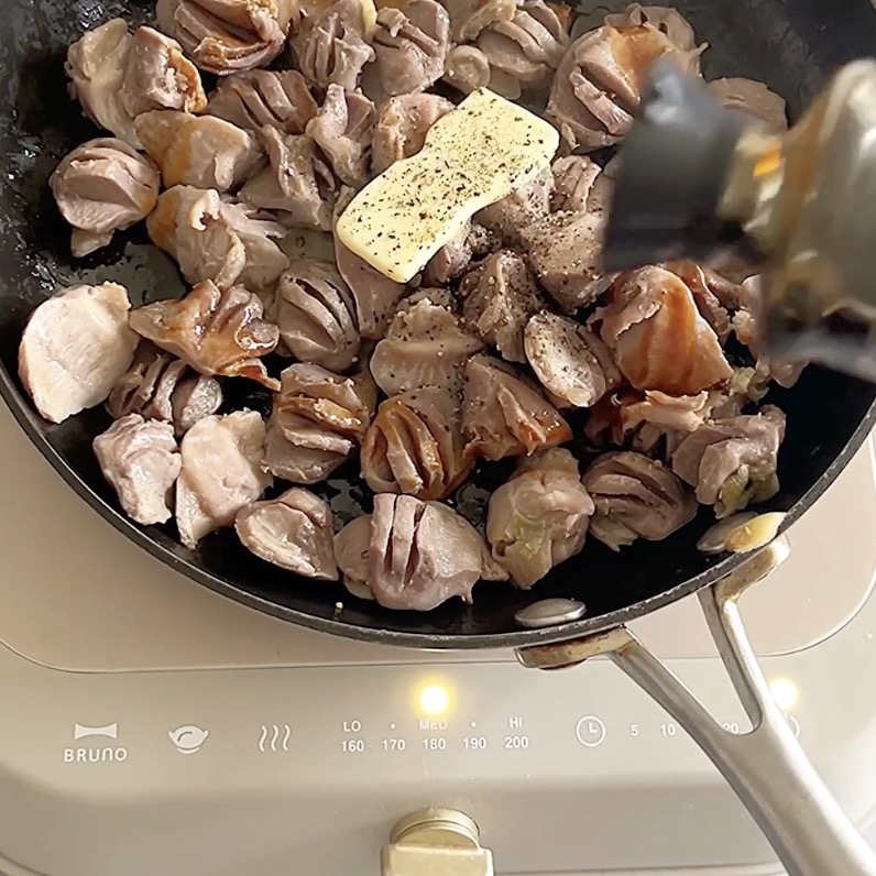 炒めた砂肝にバター、あらびき胡椒、牡蠣醤油を加えて味付けしている様子