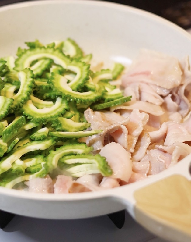 フライパンで豚バラ肉とゴーヤを炒め合わせる