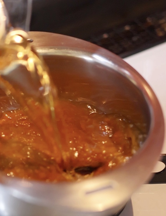鍋にカレーを入れてかつおだしを注いでいる様子