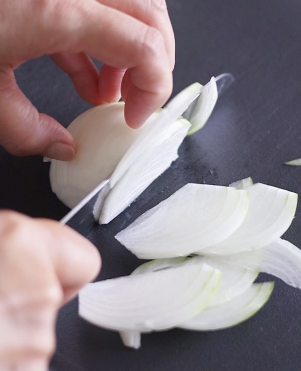 包丁で玉ねぎを薄くスライスしている手元