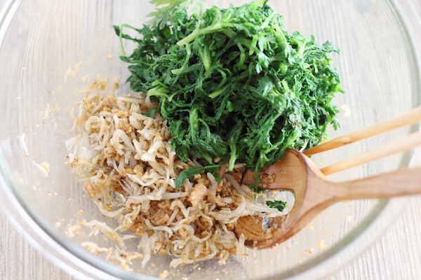 味付けしたくるみに、茹でた春菊と釜揚げしらすを加えて和える準備をしている様子。