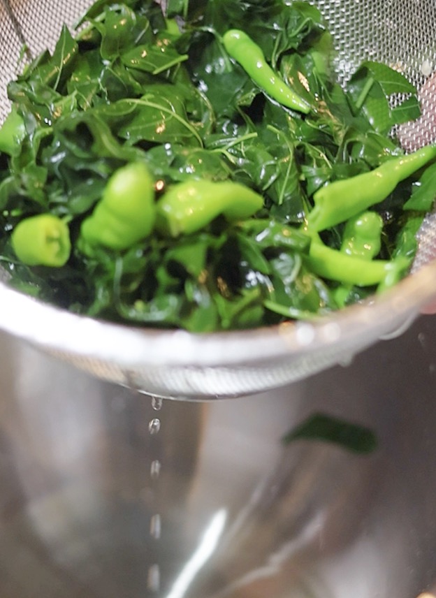 茹で上がった葉とうがらしをザルにあげ、鮮やかな緑色を保ったまま水気を切っている様子。