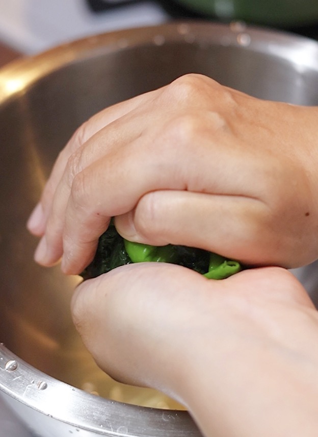 冷水に取った葉とうがらしを、両手でボール状に固く絞って余分な水分を取り除く下準備。