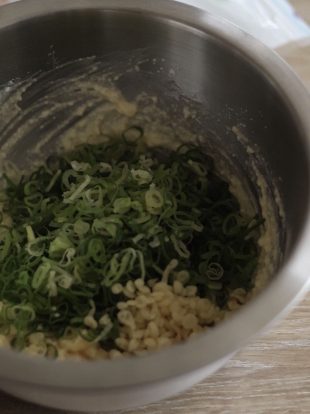 完成した豆腐ベースの生地に、たっぷりの刻みねぎと揚げ玉を加えて混ぜ合わせている様子。