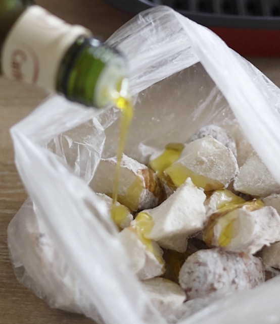 ポリ袋に入れたカット済みの菊芋に、片栗粉とオリーブオイルを加えて袋を振り、全体になじませている工程