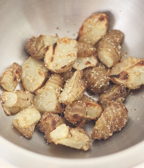 焼き上がった熱々の菊芋をボウルに移し、コンソメ顆粒と粉チーズをまぶして完成した、揚げない菊芋の唐揚げ