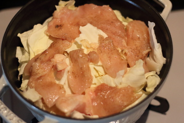 厚手のホーロー鍋に、キャベツの芯など水分の多い野菜をしき、その上に肉を置いて蒸す