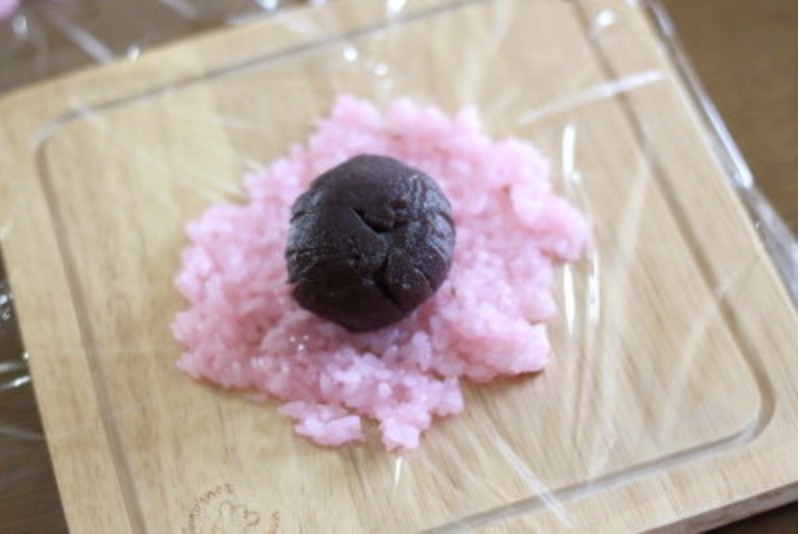 ラップの上に生地を広げ、丸めておいたこしあんを包む。