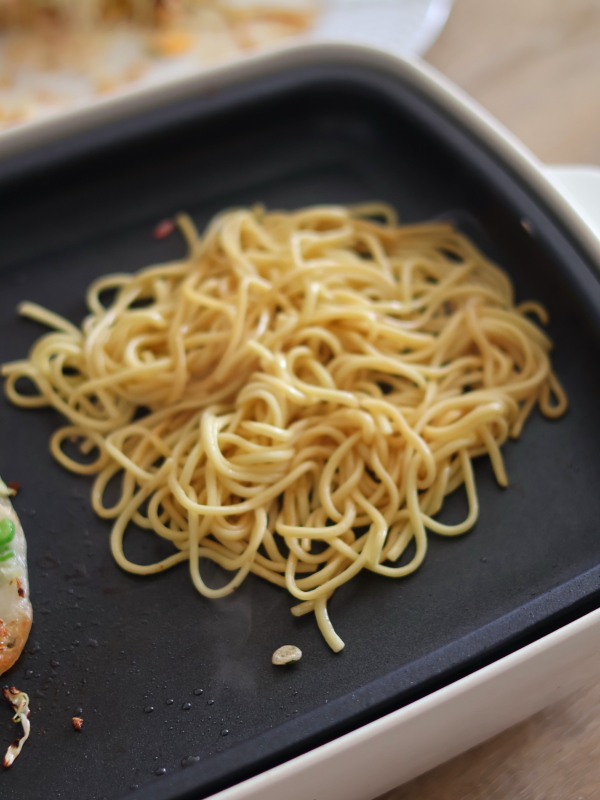 ホットプレートの空いたスペースで中華麺をほぐしながら焼き、ソース少々で下味をつけます。