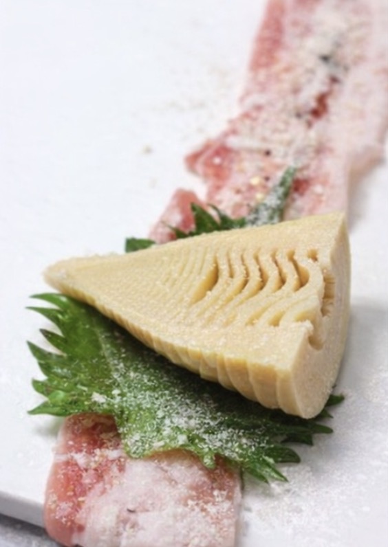 豚バラ肉を広げて、その上に大葉を置き、たけのこを巻きます。