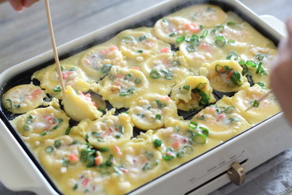 たこ焼き器を熱して油(分量外)を引き、生地を流し込んでから、たこ・天かす・紅生姜・ねぎを散らします。
熱源に近い(火が通りやすい)場所から順番に返していきます。