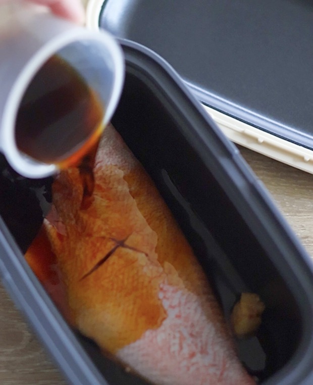 3COINSのレンジ調理器（または深い耐熱容器）に魚を入れ、（A）の調味料を回しかけます。