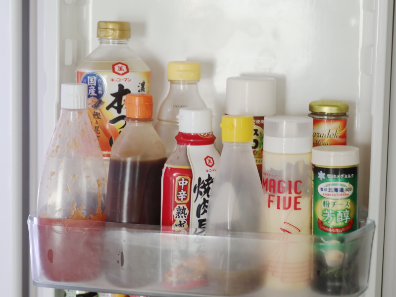 冷蔵庫のドアポケットに背の高い調味料を並べて収納している様子