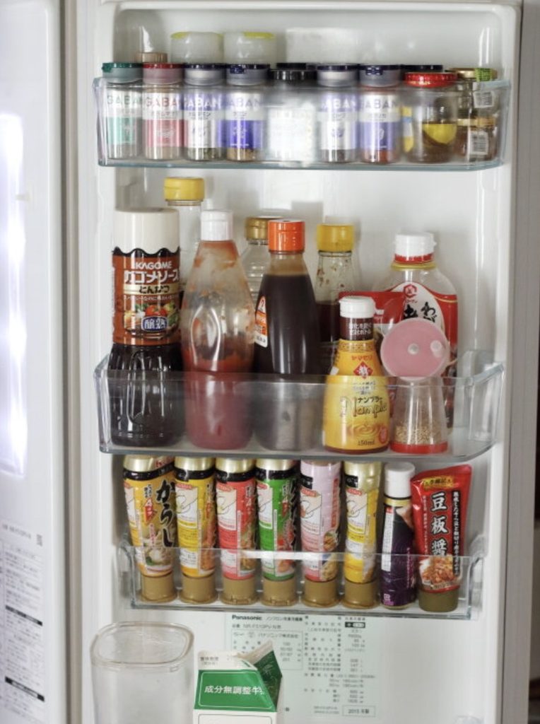 冷蔵庫の左側ドアポケットに調味料やスパイスを収納している様子